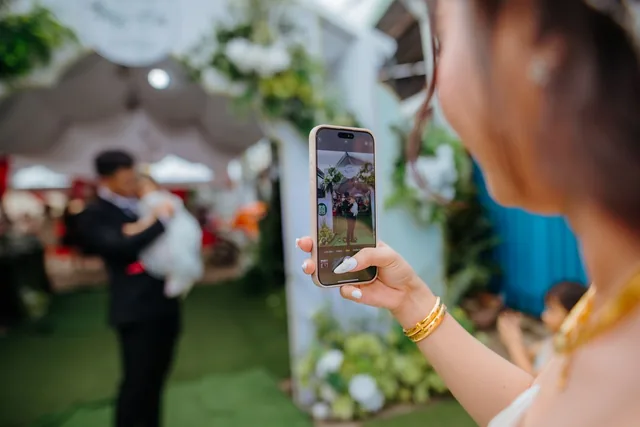 Hochzeitsgast fotografiert mit dem Smartphone eine Szene der Feier